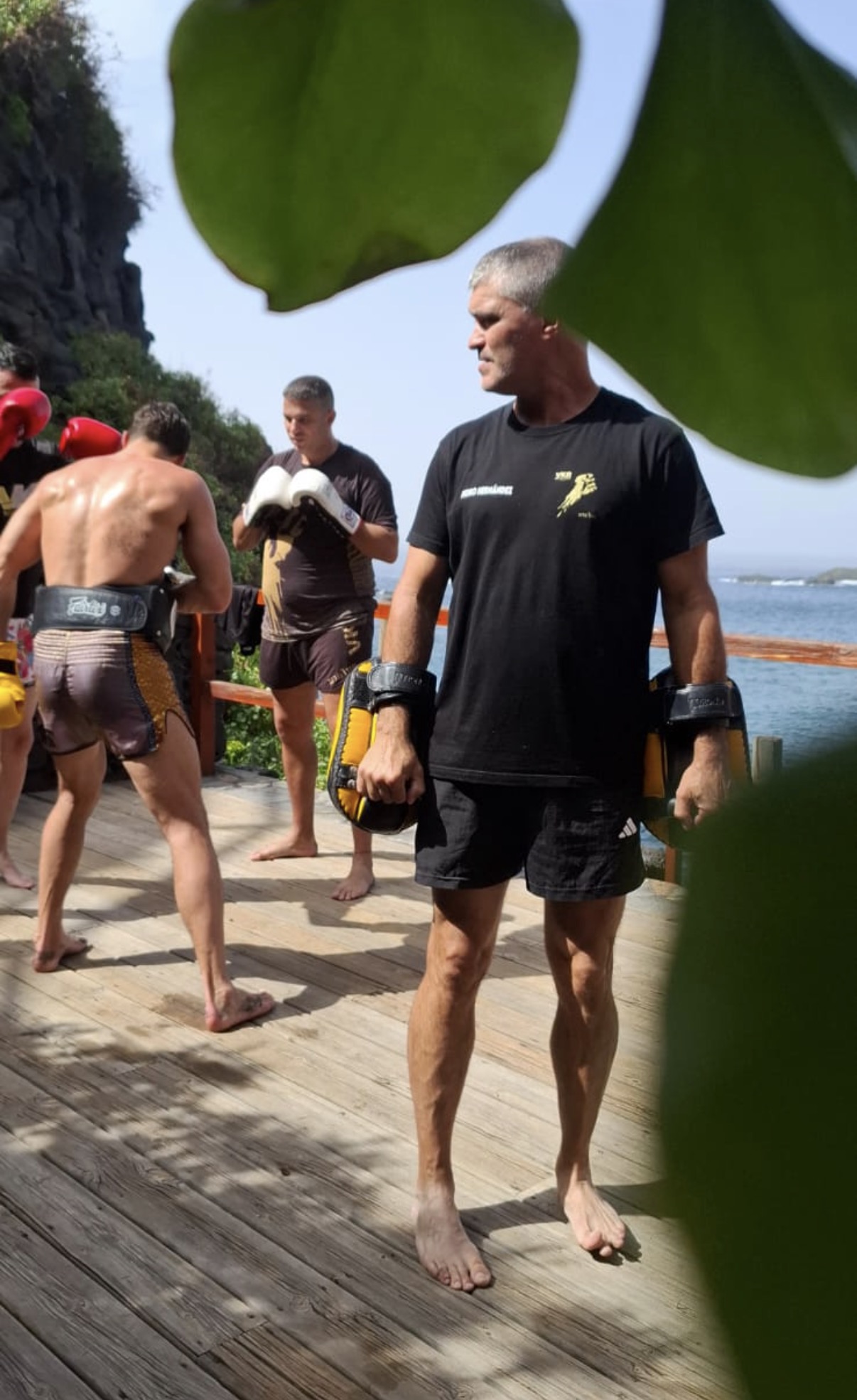 Coach Pedro holding pads on outdoor deck