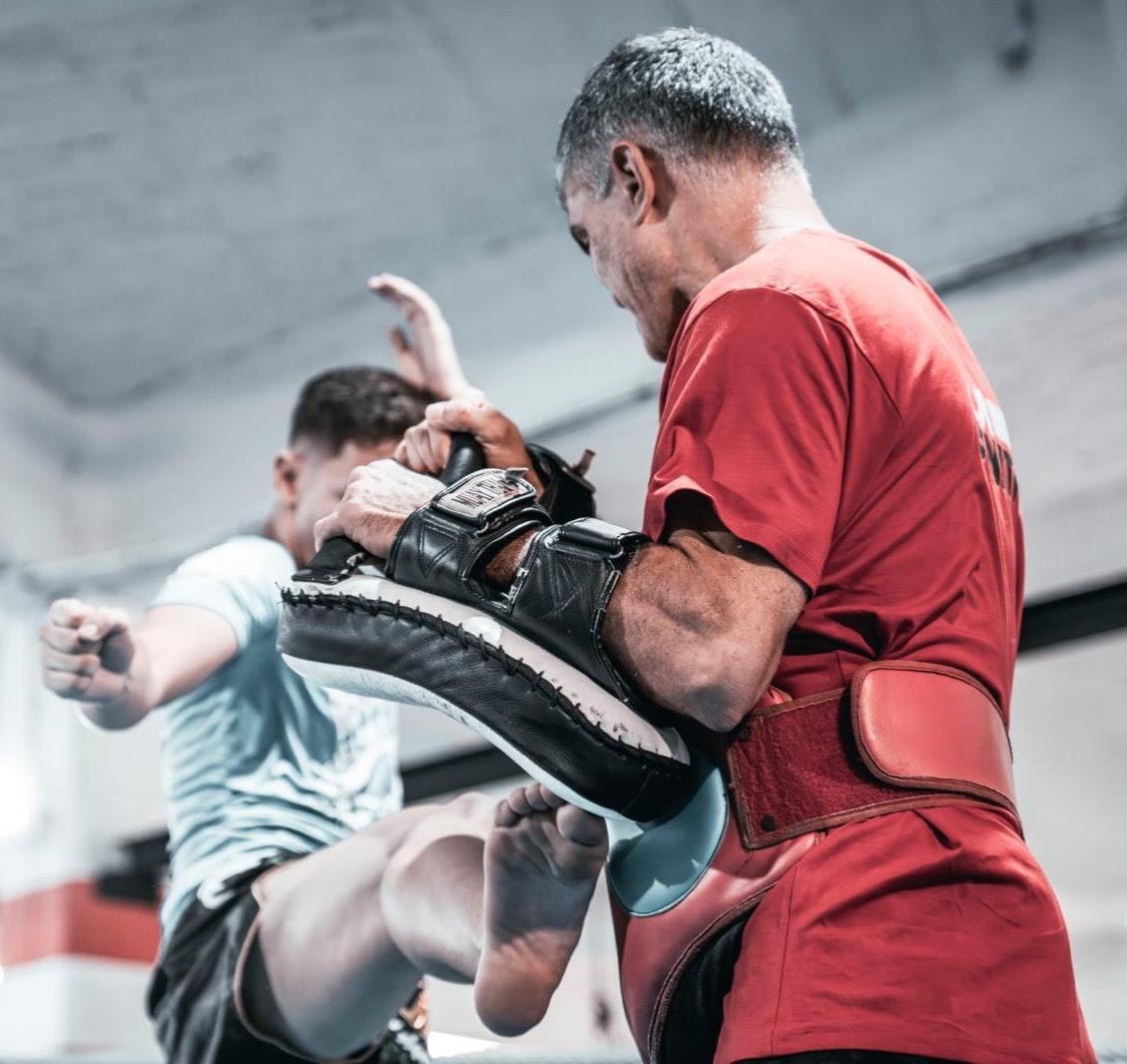Coach holding kick shield during pad work